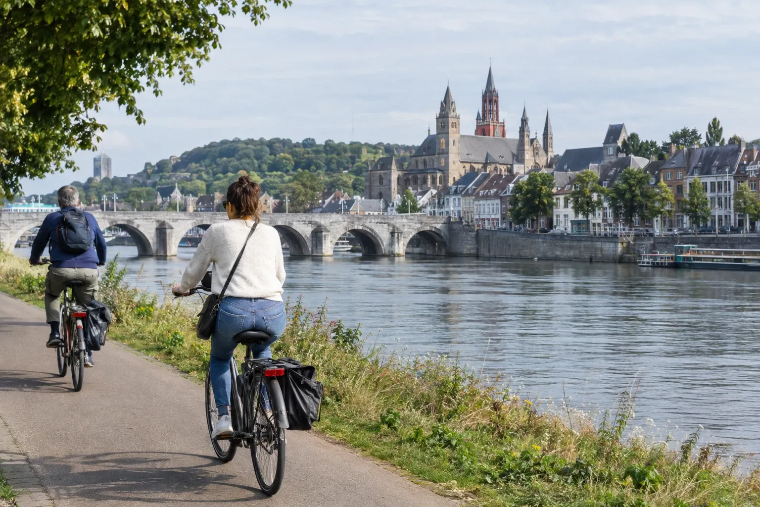Twee fietsers langs Maas fietspad richting Sint-Servaasbrug en Sint-Servaasbasiliek in Maastricht